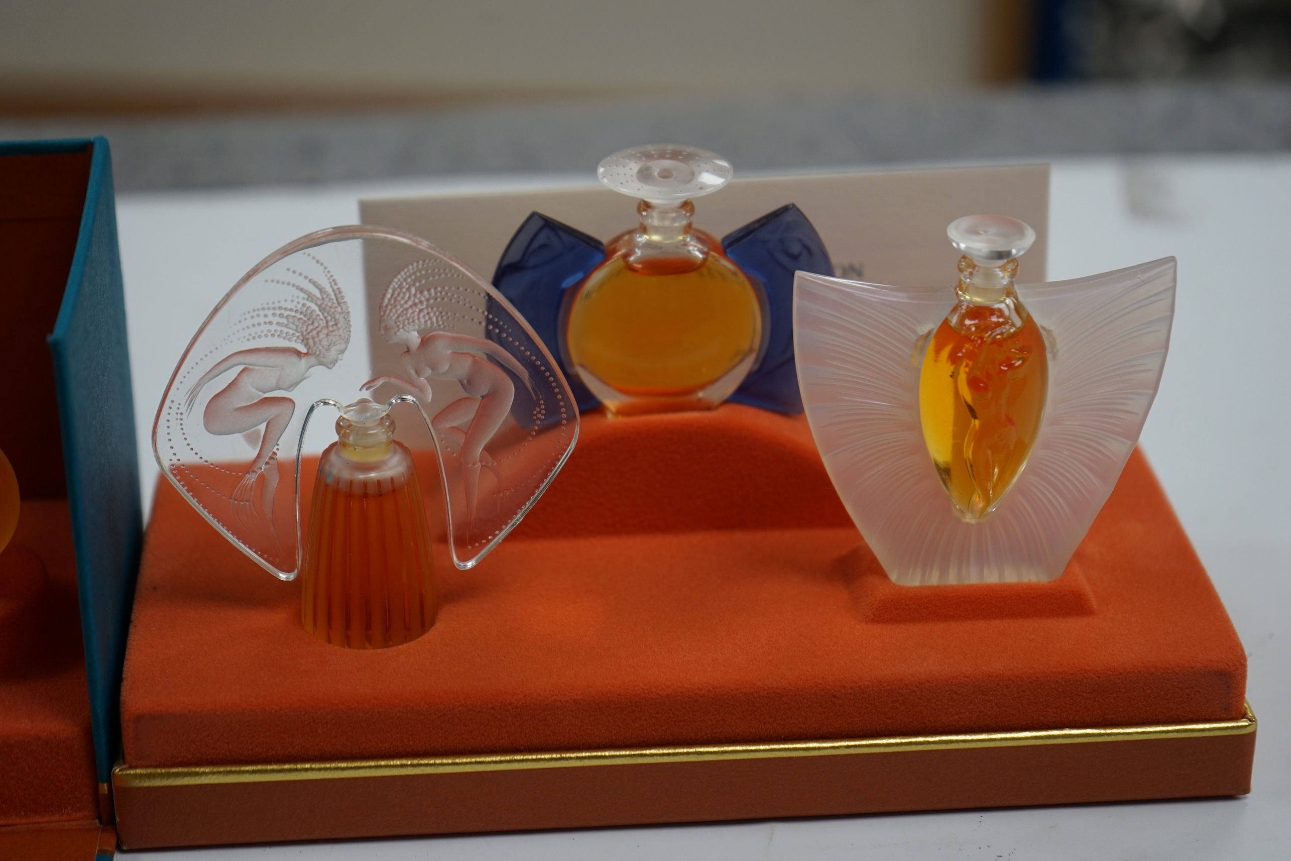 Two Lalique sets of three miniature perfume bottles. 'Les flacons miniatures' 1996-1997 and 1998-2000, boxed and sealed, tallest 7cm high. Condition - good